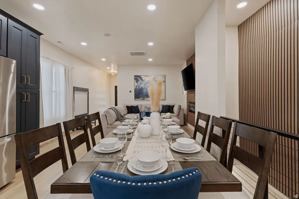 Open-concept dining area with wood-finish flooring, recessed lighting, and a linear accent wall