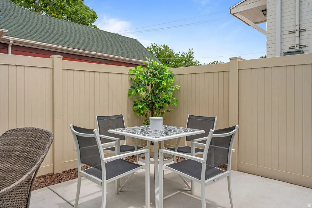 Paved patio area featuring a beige privacy fence and integrated landscaping