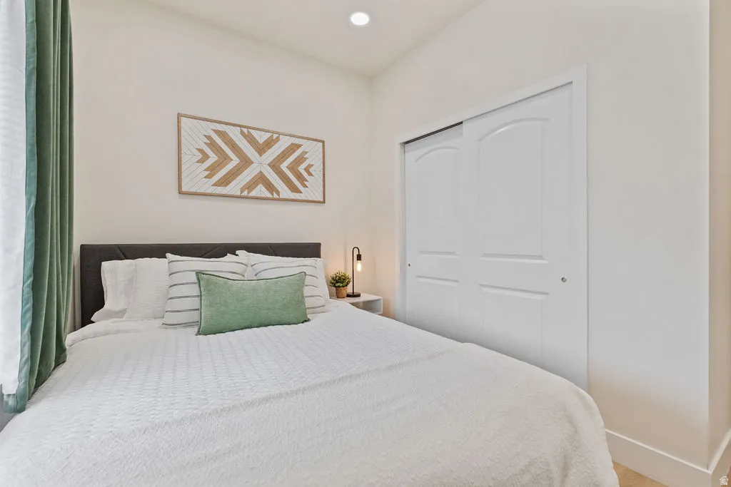 Vaulted ceiling bedroom featuring bright white walls, recessed lighting, and a bi-fold closet with arched panel details