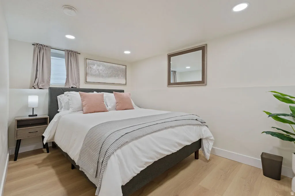 Bedroom featuring light wood-finish flooring, recessed lighting, and a window with blinds