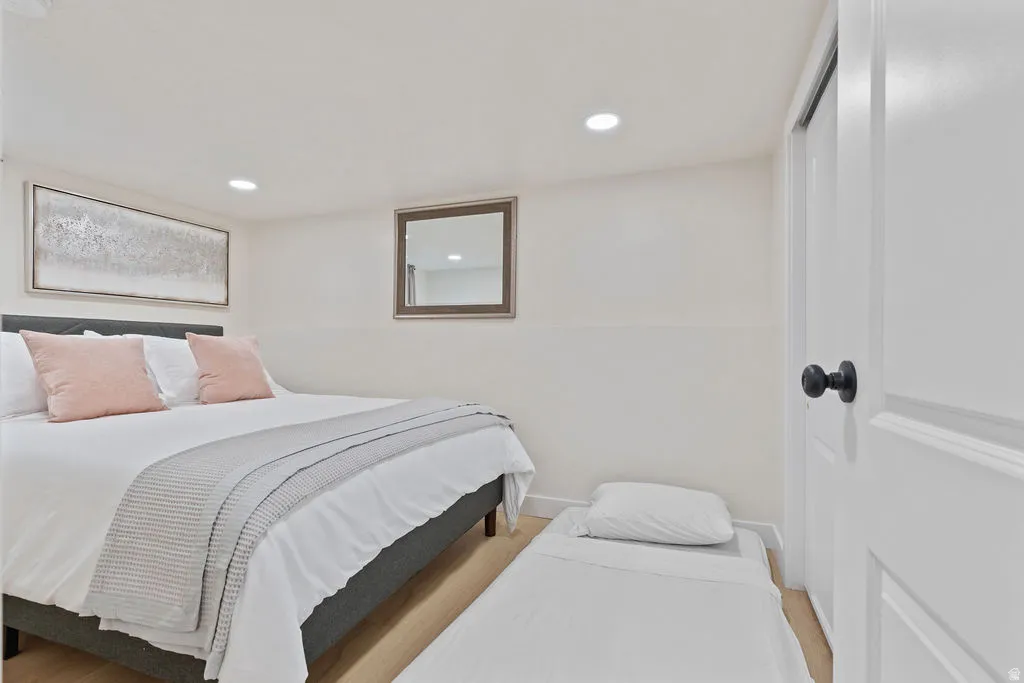 Bedroom featuring recessed lighting, light-tone wood-finish flooring, and a white interior door with matte black hardware