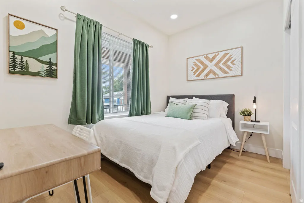 Bright room featuring wood-finish flooring and a large window with privacy blinds