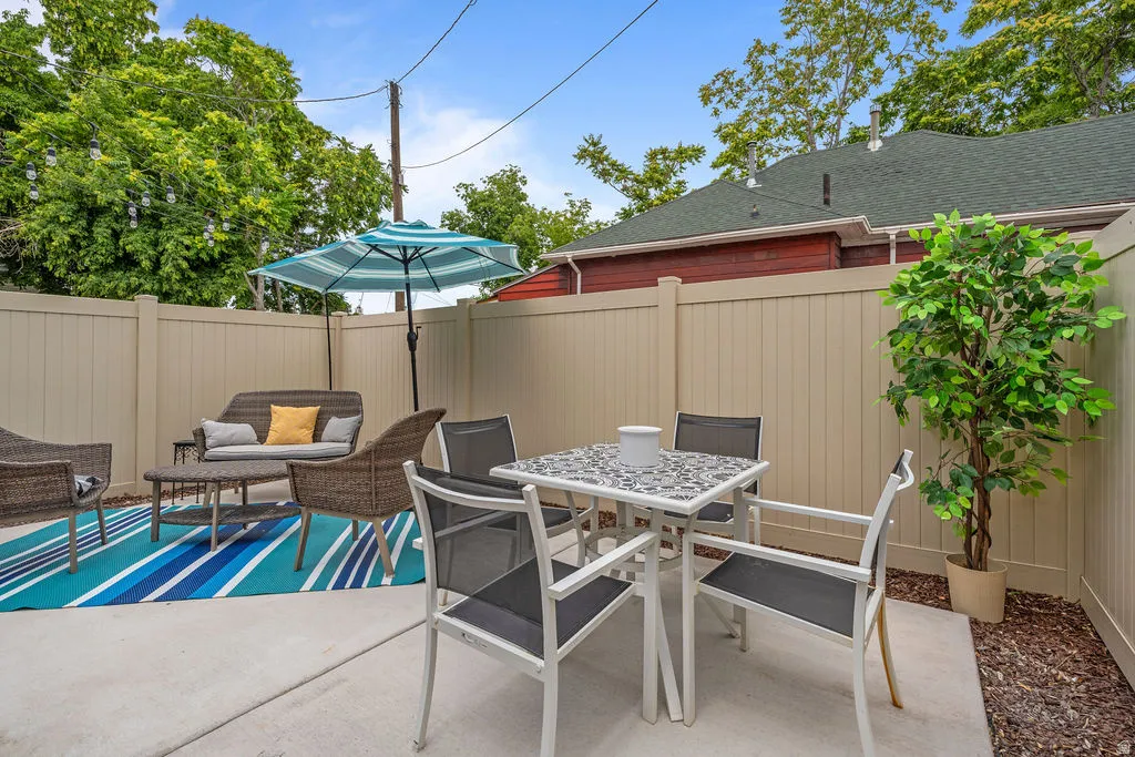 Private outdoor patio space featuring a neutral-toned privacy fence, concrete paving, and a mulched border