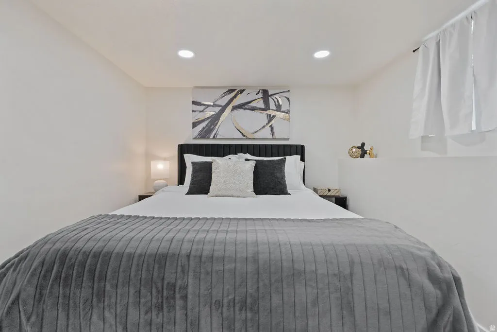 Bedroom featuring recessed ceiling lighting and a window with white curtains