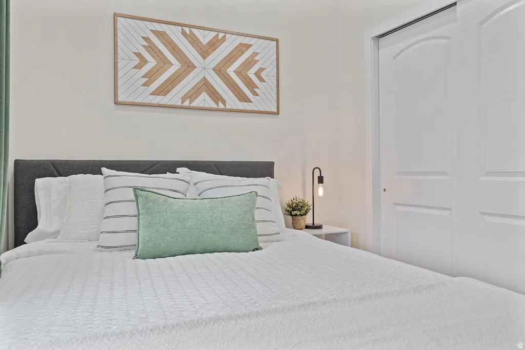 Spacious room featuring a dark upholstered headboard, a built-in closet with arched panel bi-fold doors, and neutral wall paint