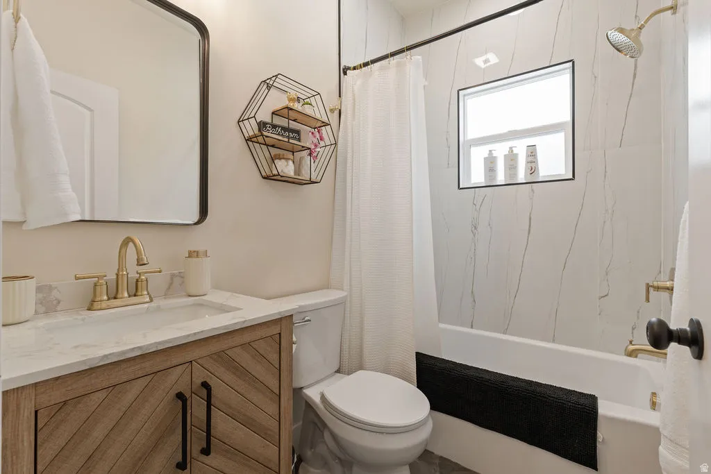 Bathroom featuring a wood-finish vanity with a light-toned countertop, a rectangular mirror, and a toilet