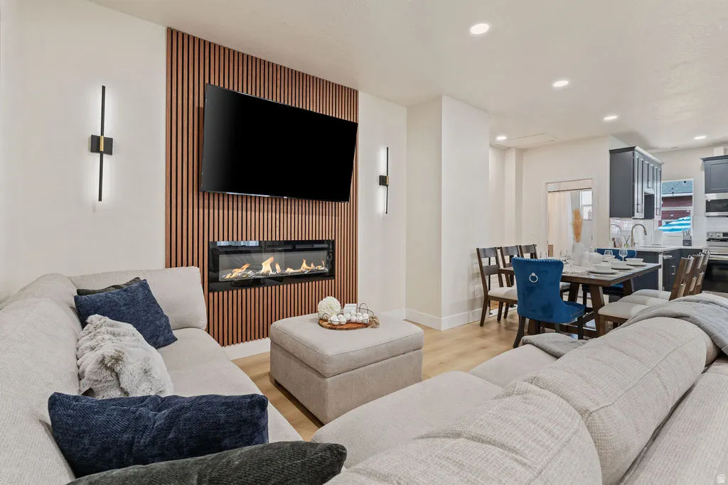 Living area featuring a slat wood accent wall with an inset linear fireplace, recessed lighting, and wood-finish flooring