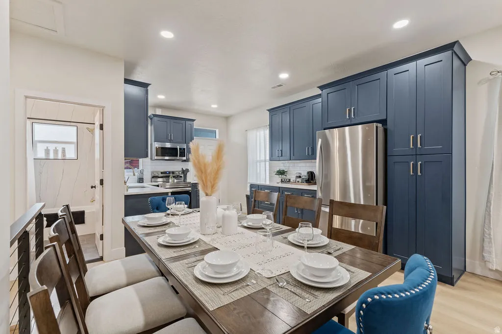 Kitchen and dining area featuring navy shaker-style cabinetry, stainless steel appliances, and recessed lighting