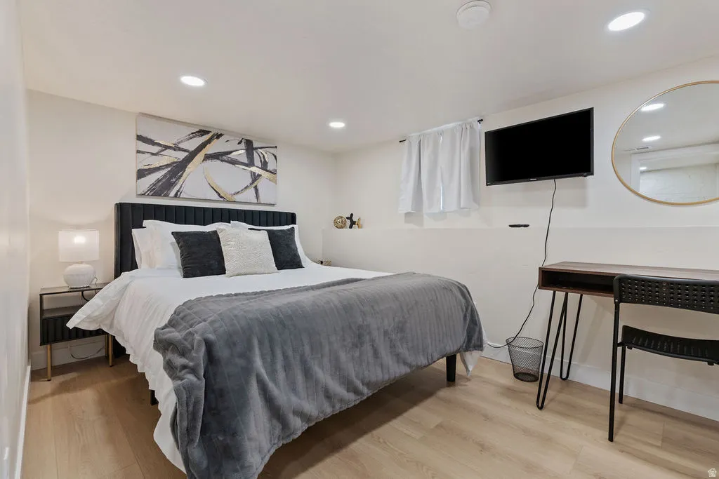 Recessed lighting illuminates the room, featuring light wood-finish flooring and a white color palette