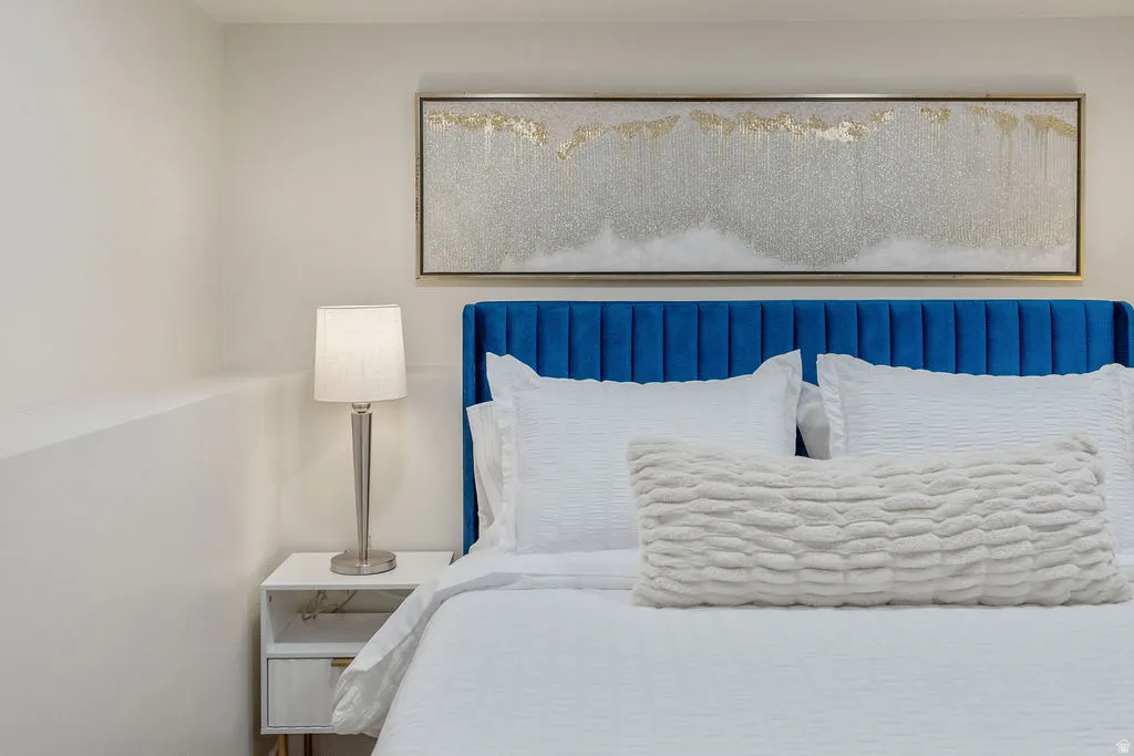 Bedroom featuring a blue channel-tufted headboard, white walls, and built-in ledge