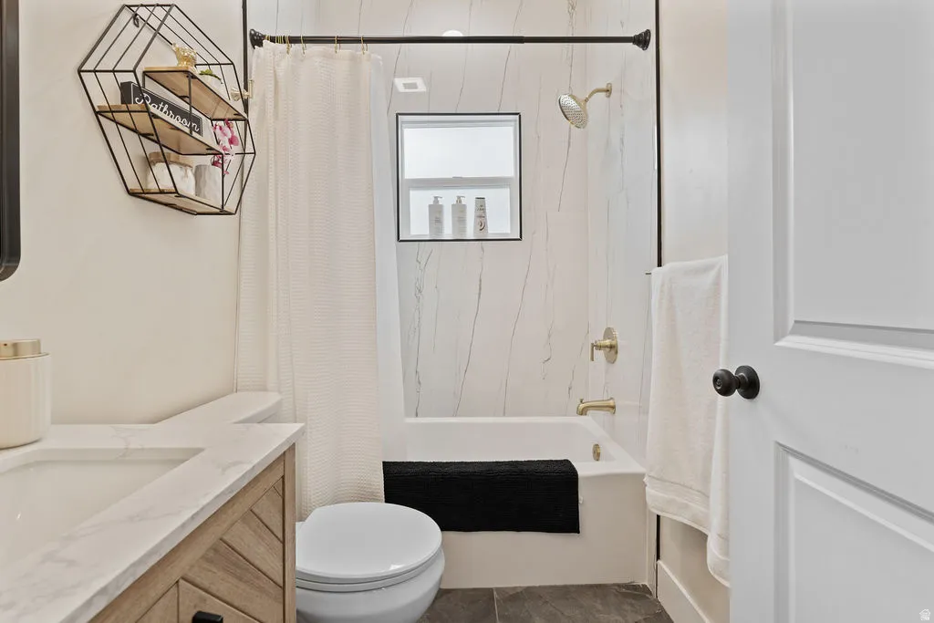Bathroom featuring a built-in tub with tile surround, gold-finish fixtures, and a window