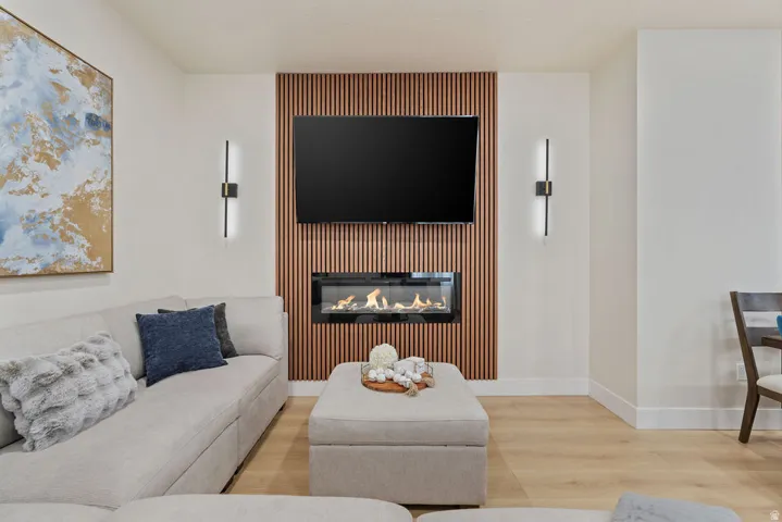 Accent wall featuring vertical wood paneling, an inset linear fireplace, and integrated modern sconce lighting