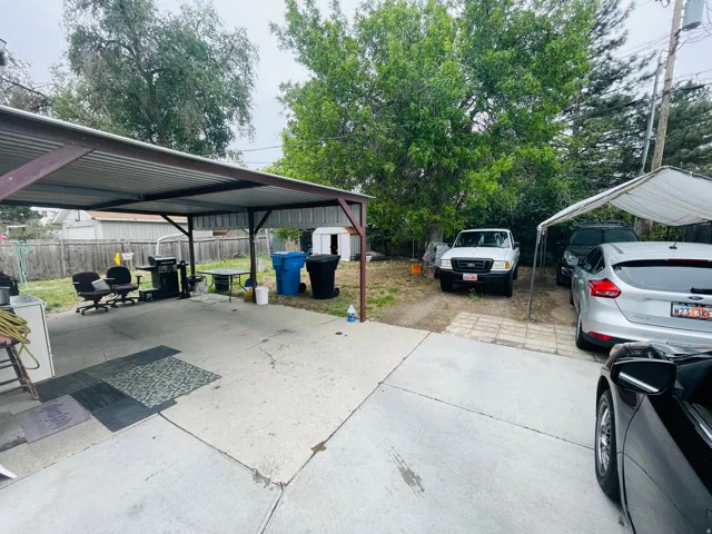 Concrete patio with a corrugated metal carport, offering covered outdoor space