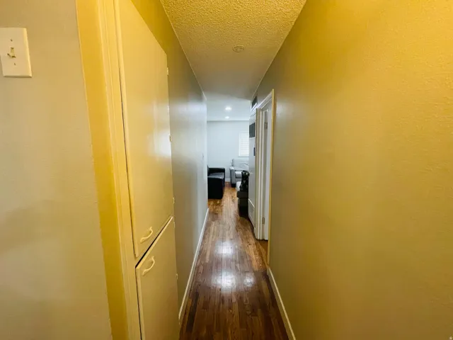 Hallway featuring wood-finish flooring, built-in cabinetry, and neutral wall tones