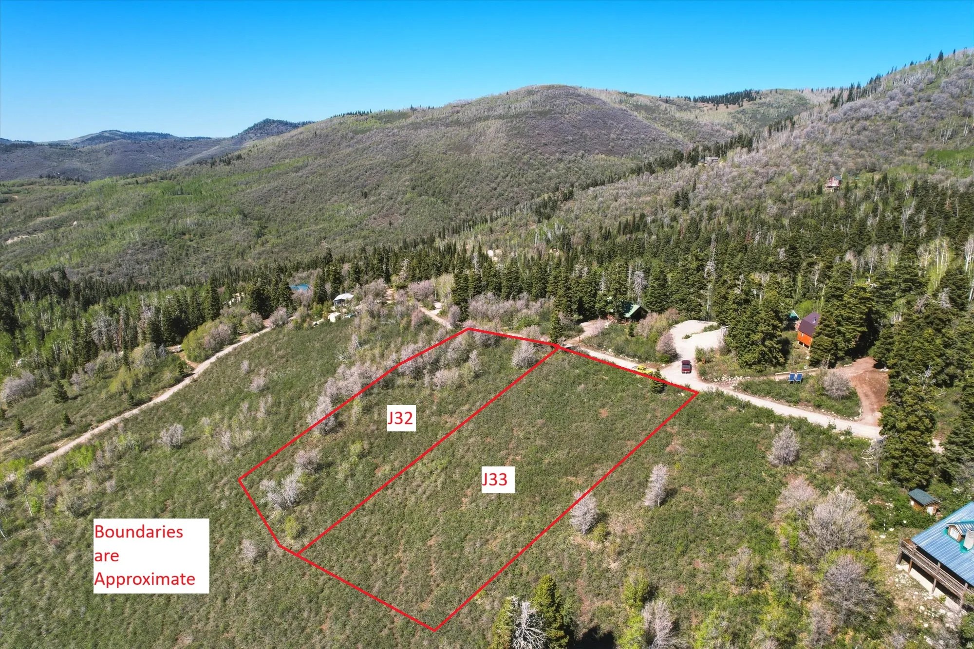 Expansive undeveloped land parcels J32 and J33, featuring a natural, mountainous landscape with varied tree cover
