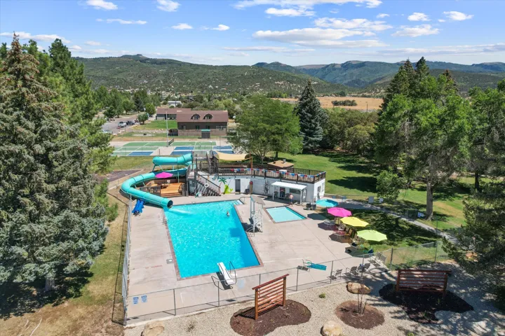 Outdoor swimming pool with a diving board, adjacent splash pool, and a winding water slide