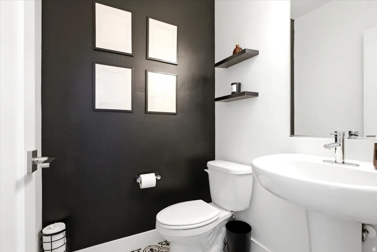 Contemporary bathroom featuring a pedestal sink, wall-mounted mirror, and black accent wall