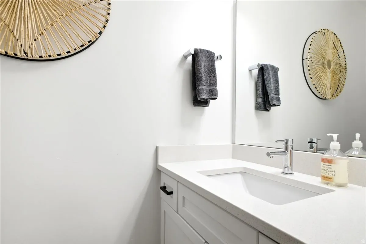 White vanity featuring shaker-style cabinetry, matte black hardware, and a light-toned countertop