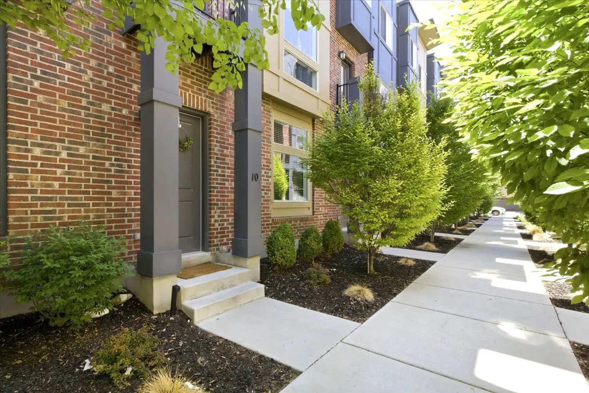 Brick exterior with a dark gray entry door, concrete steps, and a covered porch supported by two dark gray columns