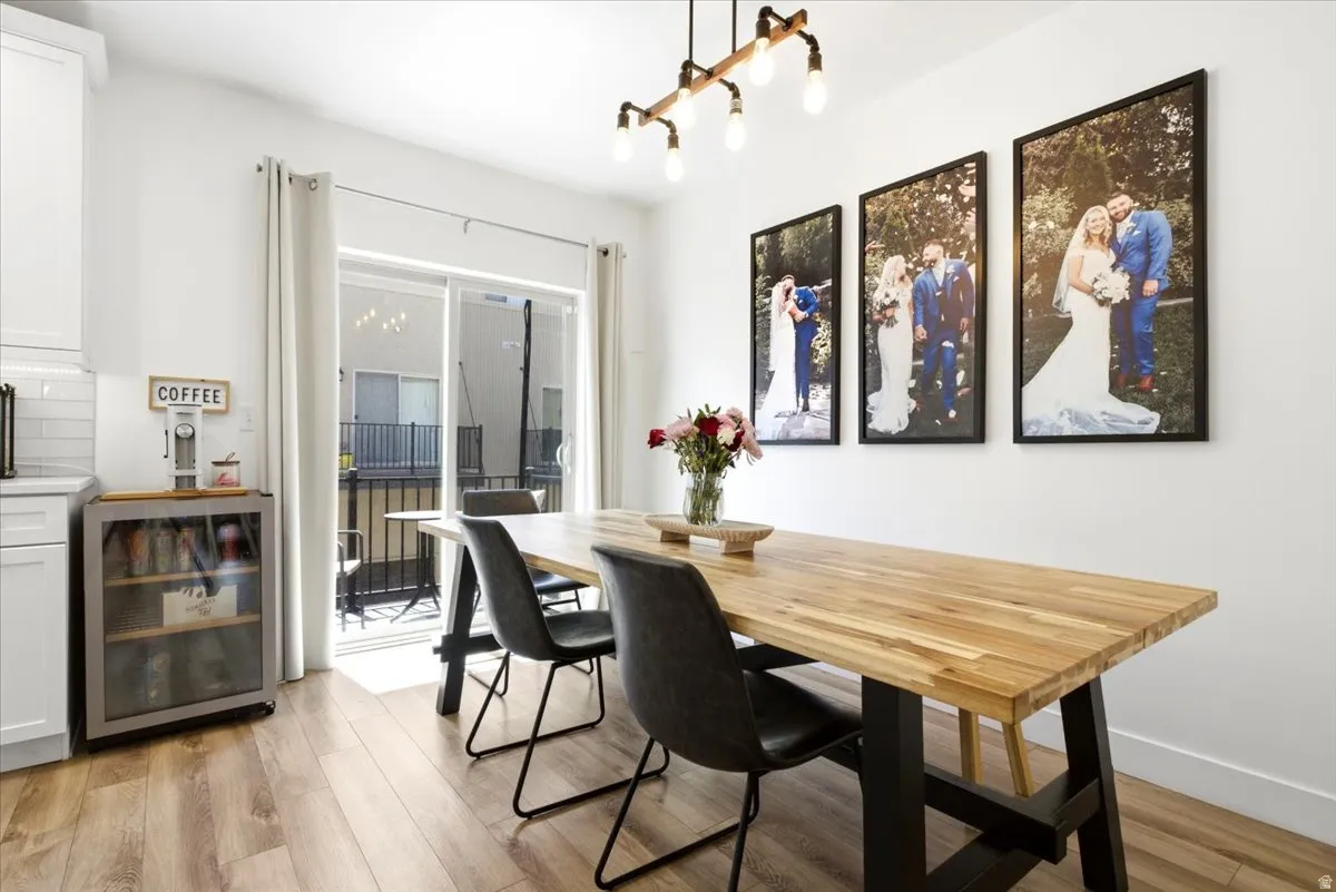 Dining area featuring wood-finish flooring, a contemporary chandelier, and direct access to an exterior patio through sliding glass doors