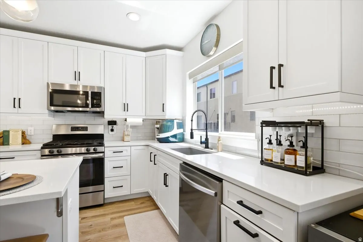 Modern kitchen featuring white shaker cabinetry, stainless steel appliances, white subway tile backsplash, and light-toned countertops