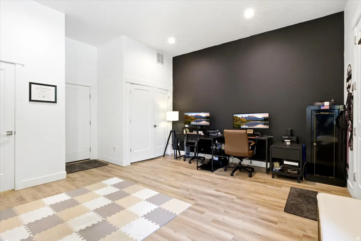 Neutral tone walls, wood-finish flooring, recessed lighting, and a dark accent wall