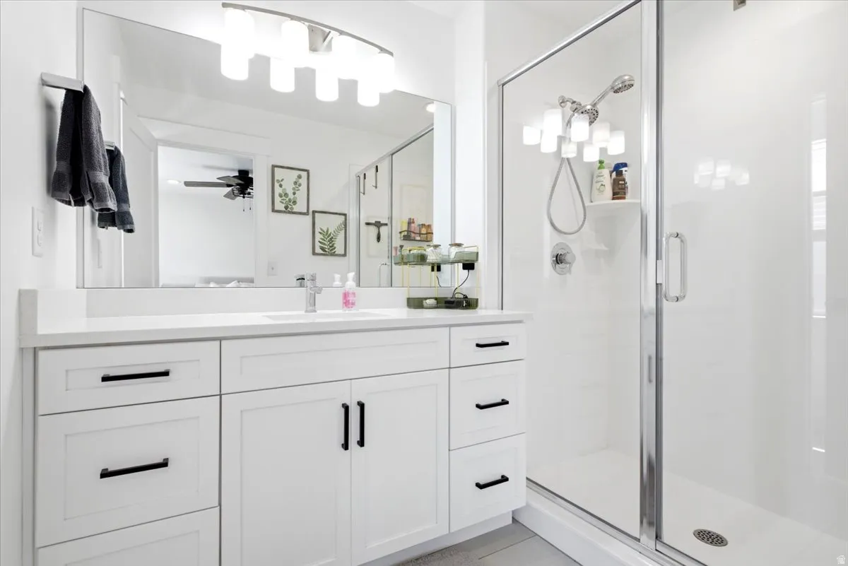 White vanity with shaker-style cabinetry and matte black hardware, featuring a white countertop and undermount sink