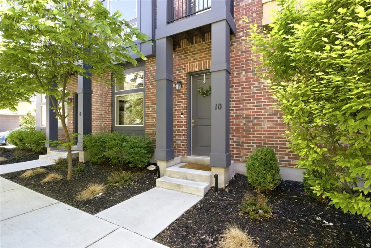 Brick facade townhome featuring modern gray trim and a covered entry