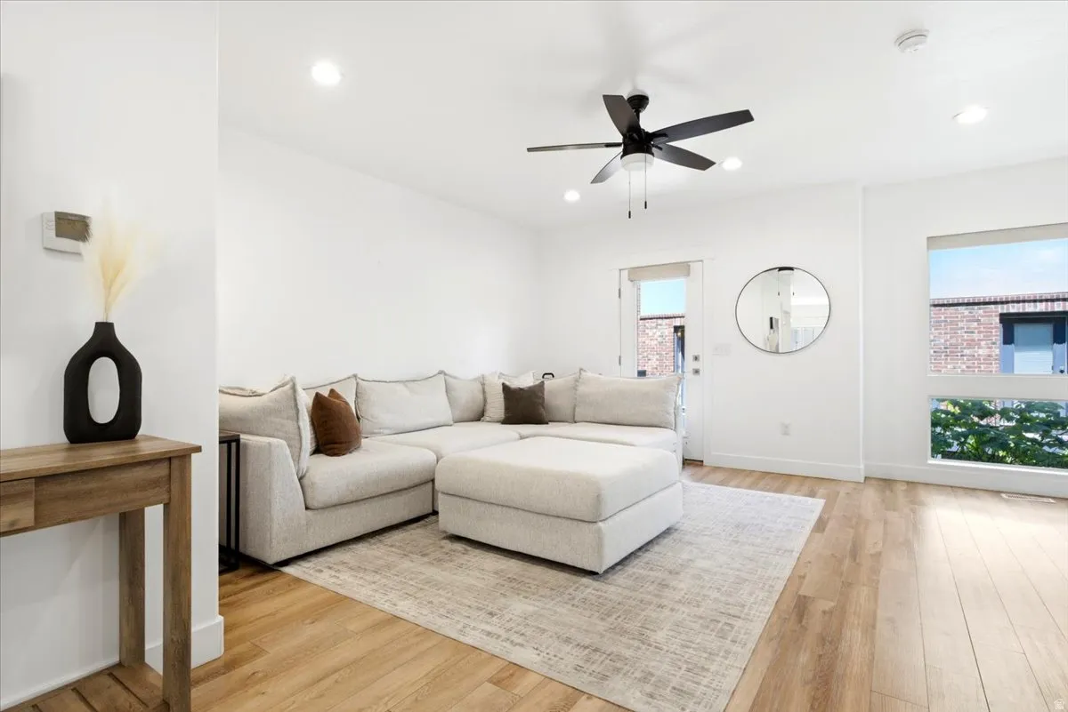 Open-concept living space featuring high ceilings, wood-finish flooring, recessed lighting, and a modern ceiling fan