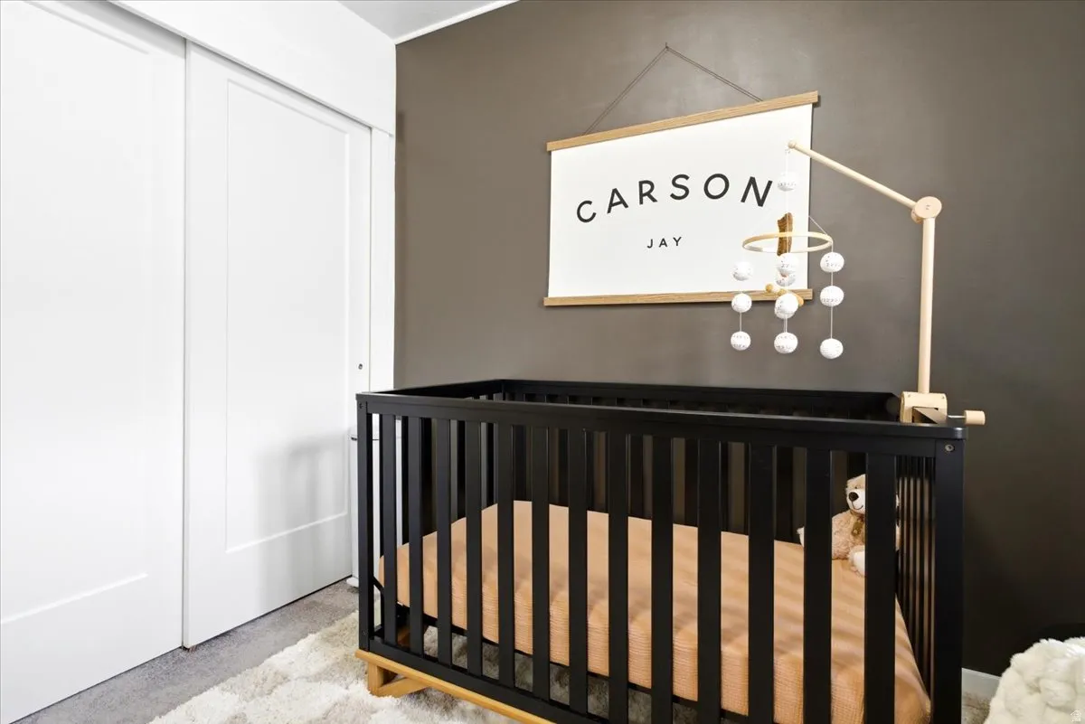 Interior room featuring a dark accent wall, white sliding closet doors, and light-colored carpeting