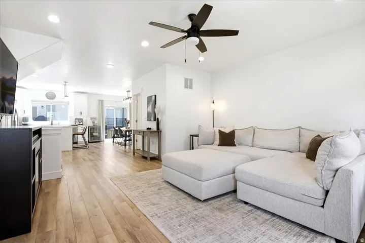 Open-concept living area featuring wood-finish flooring, recessed lighting, a ceiling fan, and white walls