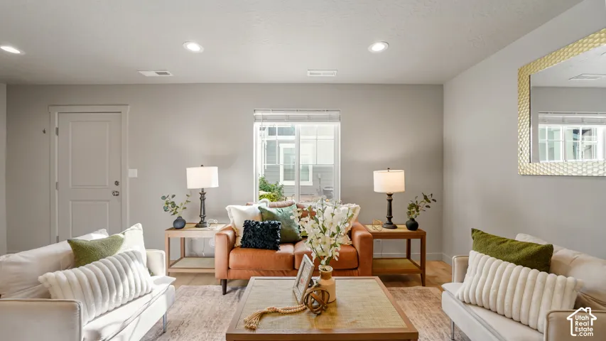 Recessed lighting, wood-finish flooring, and a window with blinds provide a bright interior