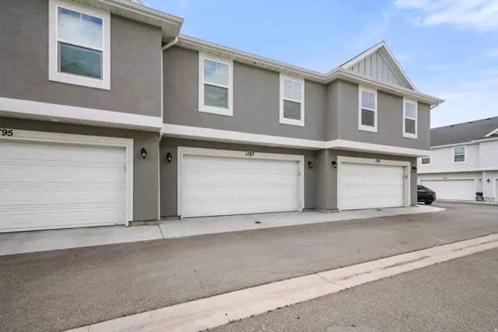 Multi-level townhome exterior featuring contemporary grey stucco and white trim