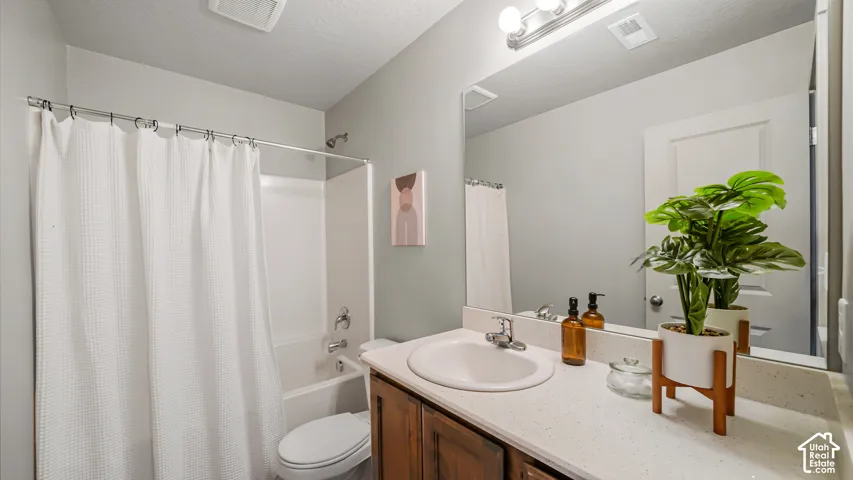 Primary full bathroom with an integrated shower and tub, a single vanity with an oval basin, a solid surface countertop, and an expansive wall-mounted mirror