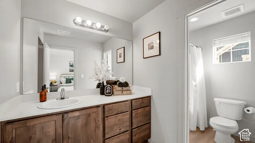 Primary bathroom wood-finish vanity with a white countertop and integrated sink