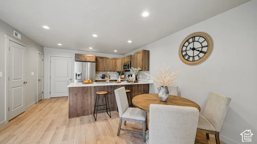 Kitchen with stainless steel appliances, wood-finish cabinetry, a central island with a light-toned countertop, and recessed lighting