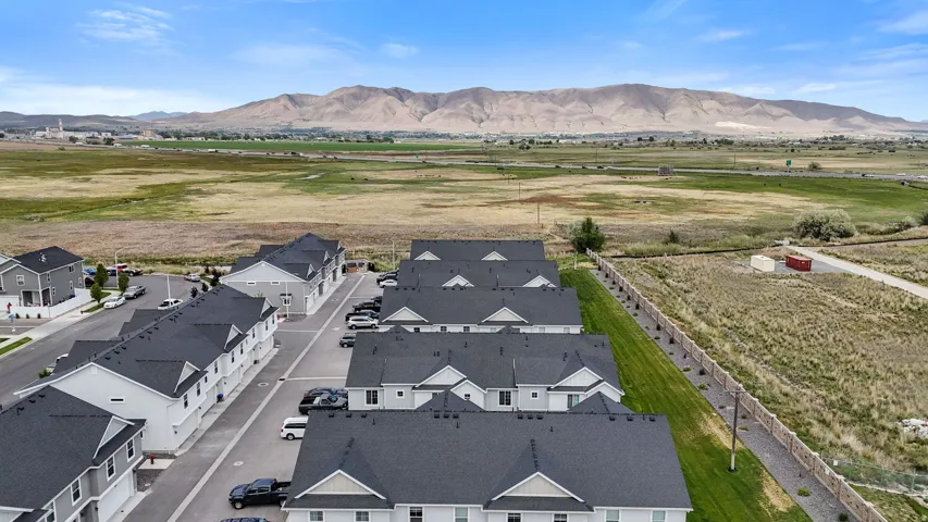 Modern residential development featuring multi-story townhomes with dark shingle roofs and light-colored siding