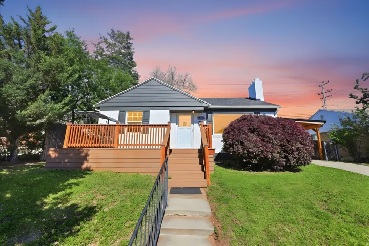 Exterior featuring white siding, dark gray gables, and a prominent front deck with wooden railing