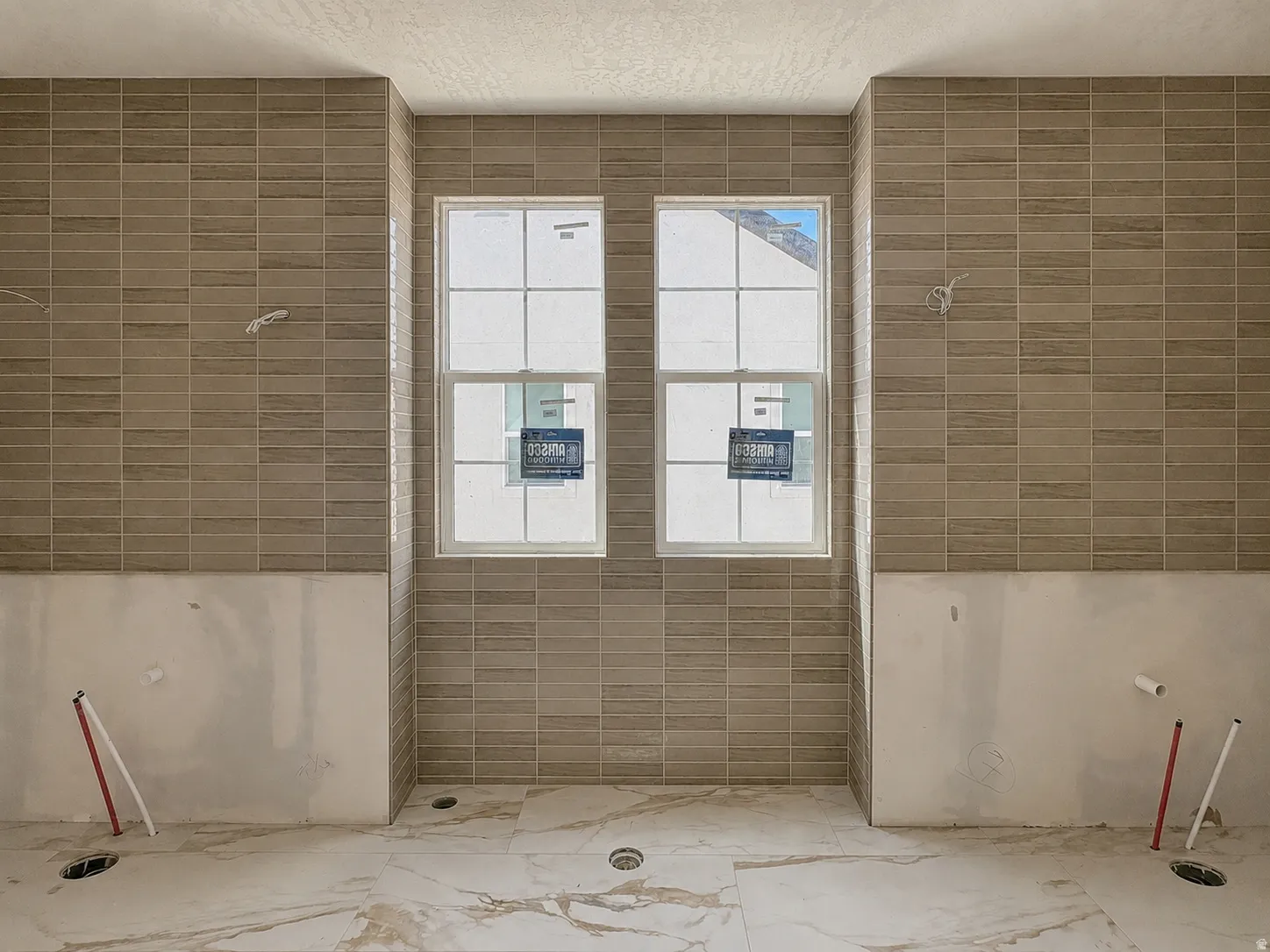 Spacious bathroom featuring two double-hung windows, horizontal subway tile accents, and marble-look floor tiles