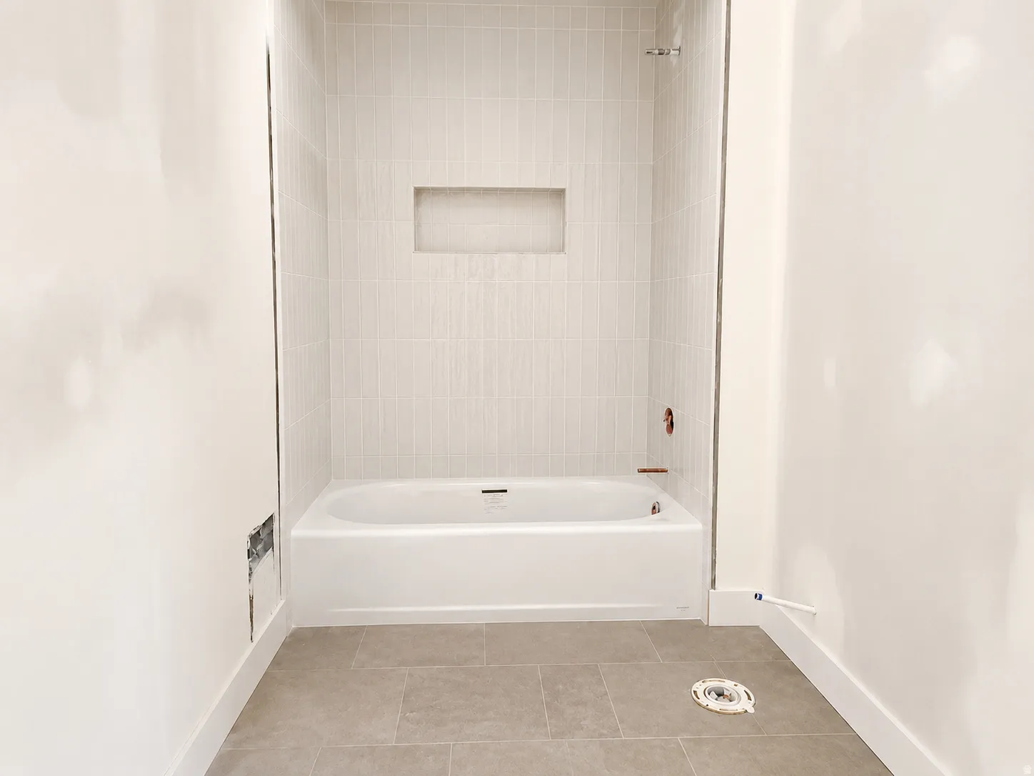 White tub and shower combination with light-toned rectangular tile surround