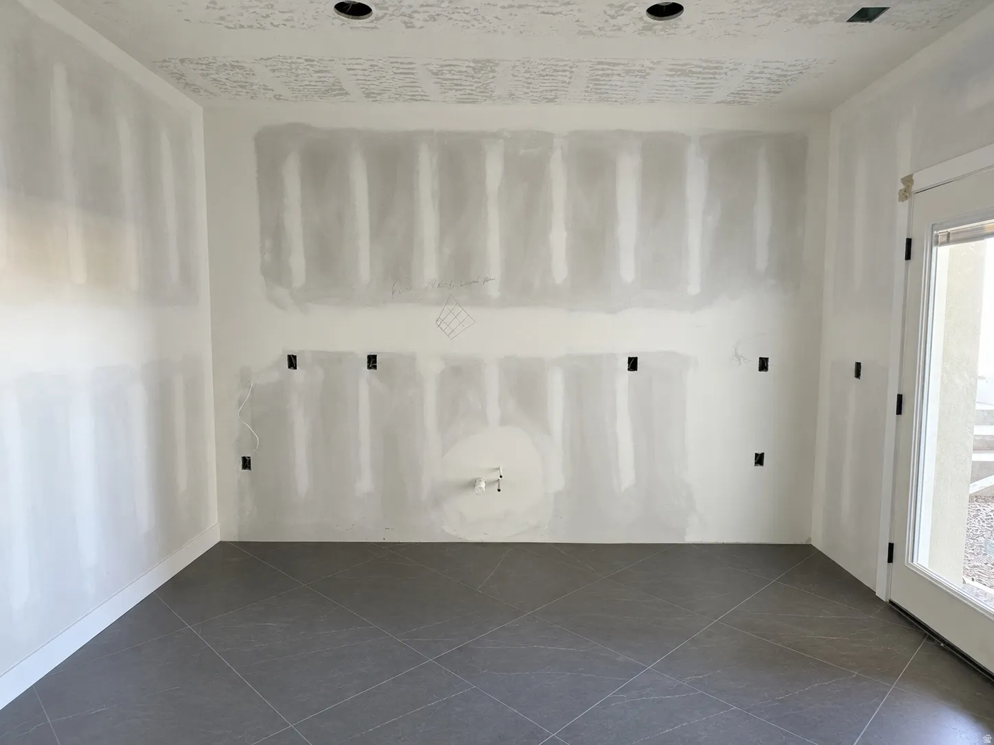 Interior space featuring unfinished drywall, recessed lighting, and large format tile flooring