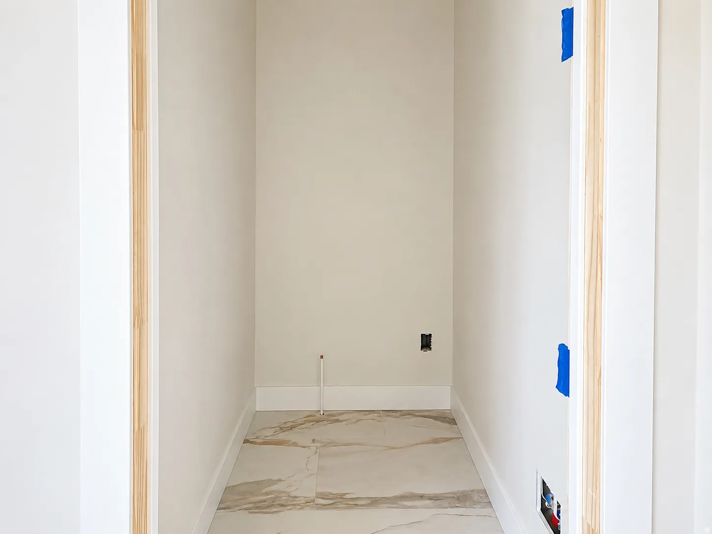 Alcove featuring large format stone-look tile flooring, light-toned walls, and white trim