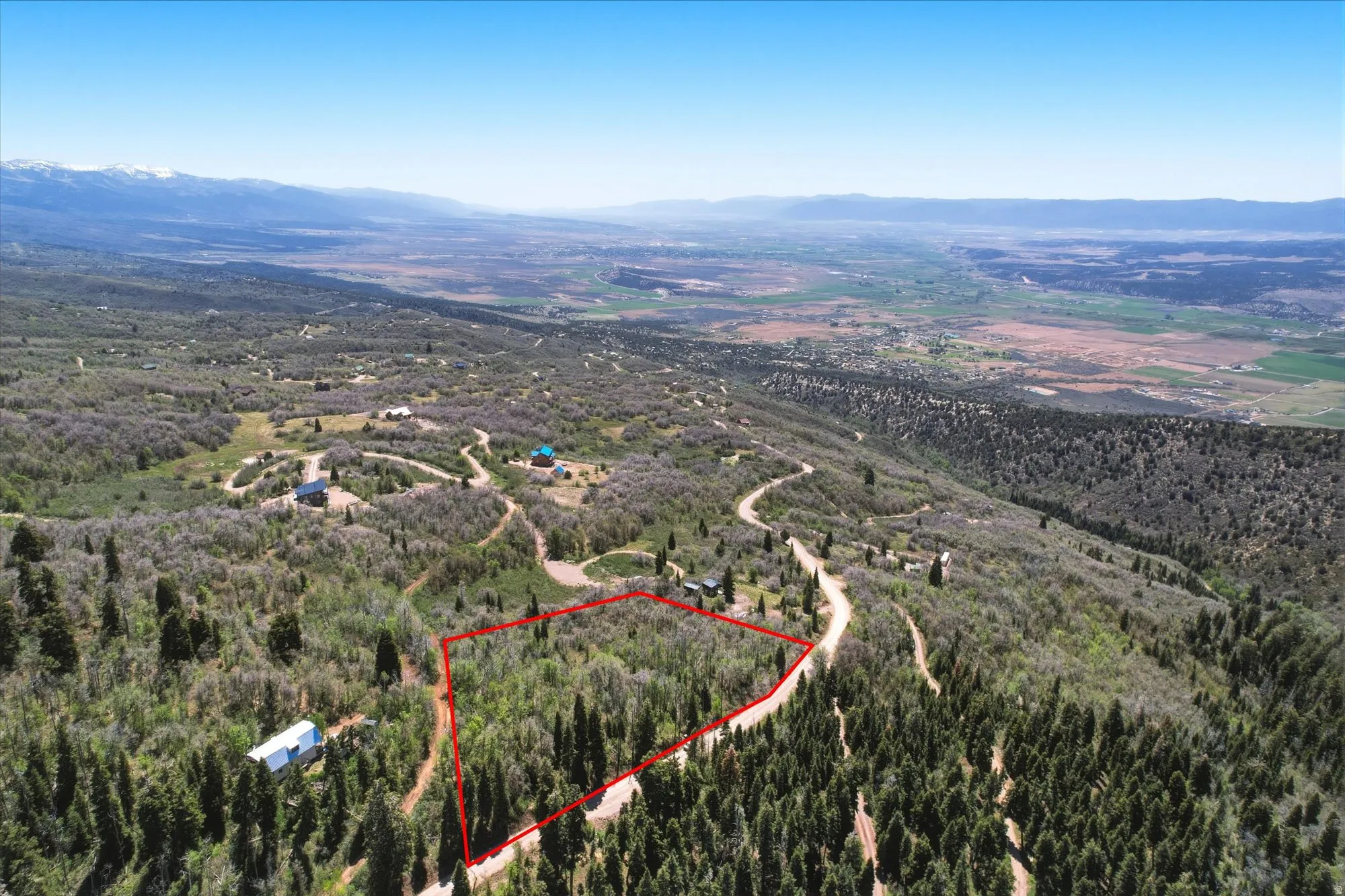 Expansive forested terrain outlined in red, featuring a winding dirt road and distant mountain ranges