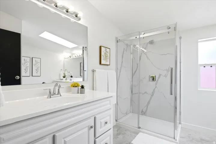 Contemporary bathroom featuring a white vanity with integrated sink, chrome faucet, and a large mirror with vanity lighting