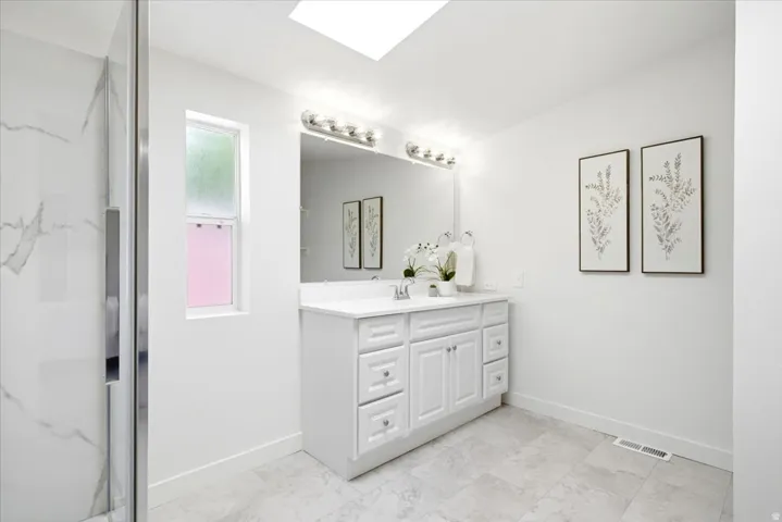 Bathroom featuring a white shaker-style vanity with a white countertop and rectangular undermount sink