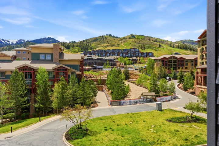 Mountainous landscape featuring multiple multi-story residential buildings, green hillsides, and paved roadways