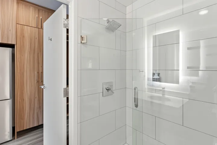Contemporary bathroom featuring a spacious glass-enclosed shower with a rainfall showerhead and wall-mounted controls