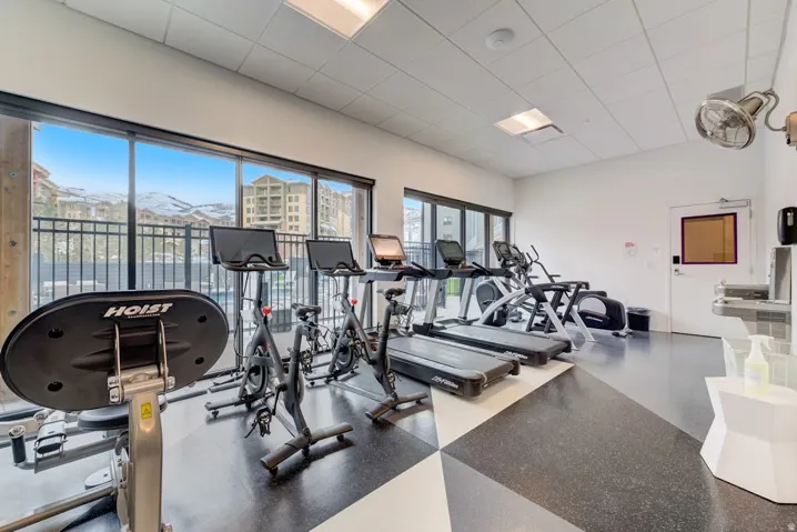 Fitness area featuring full-height glass doors, a patterned rubber floor, and a mountain backdrop