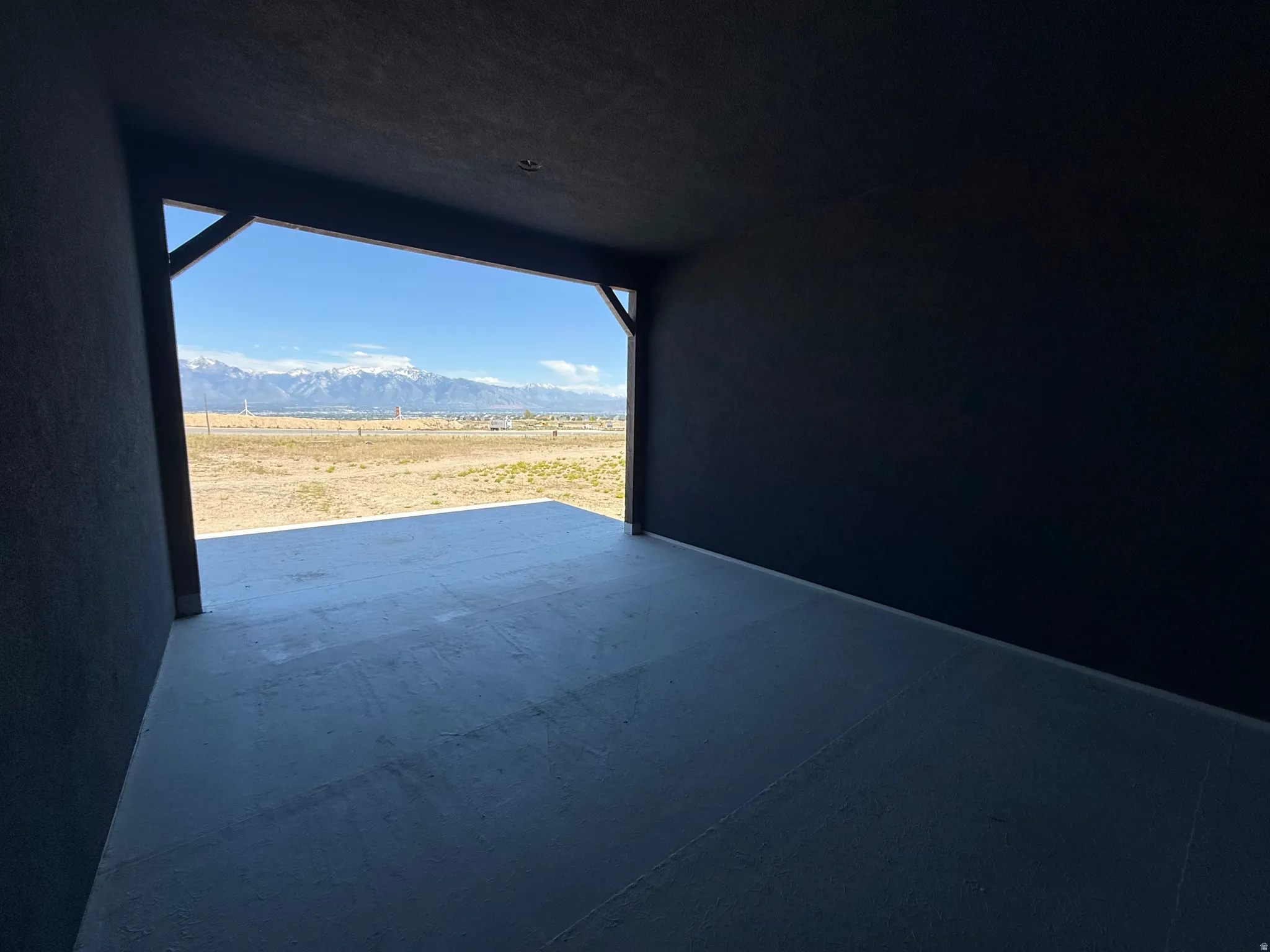 Covered patio featuring a concrete floor and dark-painted walls