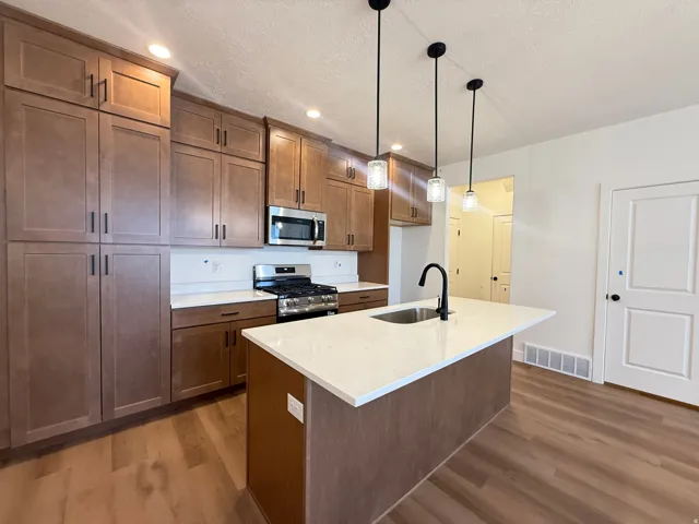 Kitchen featuring a central island with an quart countertops, extensive wood-finish cabinetry to the ceiling, stainless steel appliances, and recessed lighting